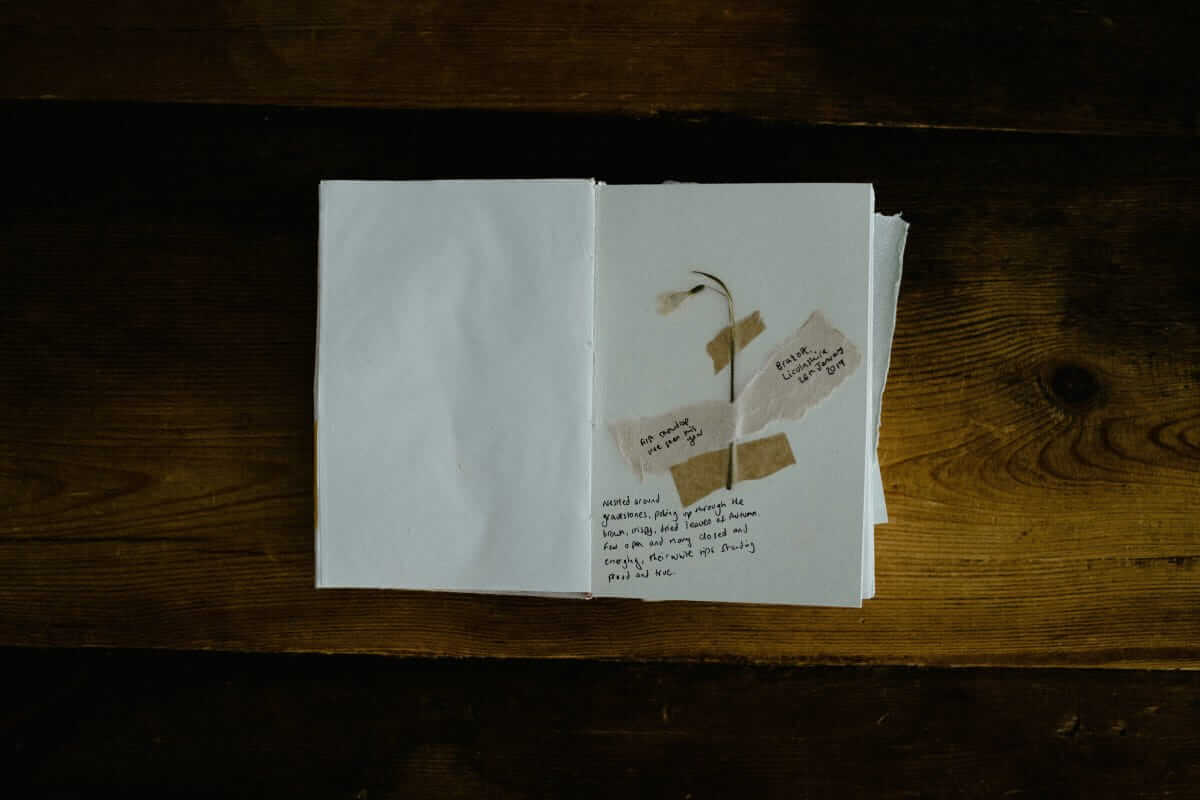 Babybuch (Offenes Erinnerungsbuch auf einem Holztisch mit getrockneter Blume und handgeschriebenen Notizen)