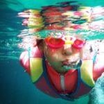 Schwimmen lernen / Kind mit Taucherbrille schwimmt unter Wasser
