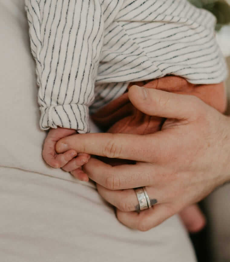 Baby beruhigen / Baby hält den Finger einer Bezugsperson fest – Nähe und Sicherheit durch Berührung.
