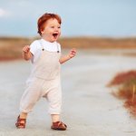 Lauflernschuhe (adorable redhead toddler baby boy in jumpsuit running through the summer road and field)