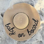 1. Lebensjahr, 0 Jahre / Ein Hut mit der Aufschrift Baby an Bord im Sand