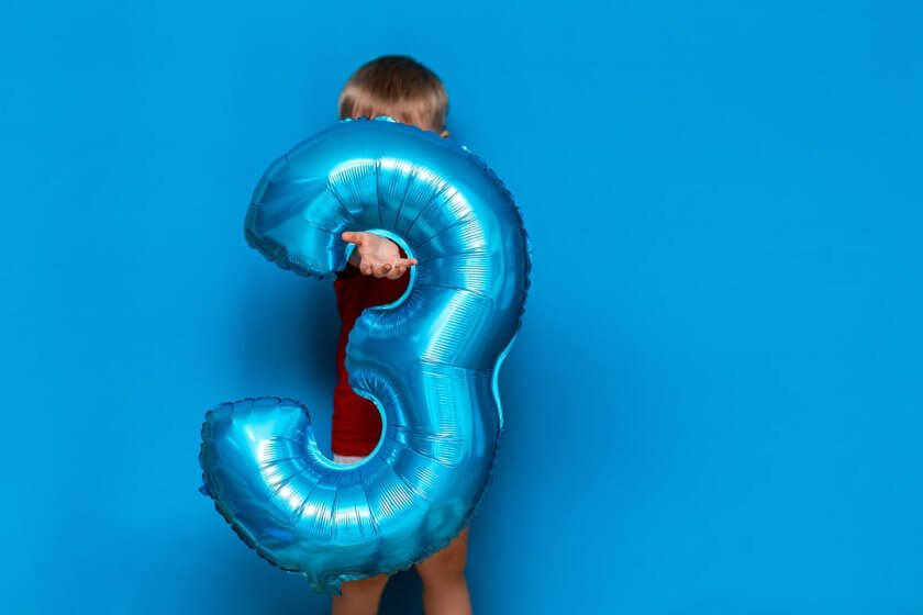 3. Lebensjahr (small cute blonde boy on blue background holding foil-coated sphere baloon blue colour. happy birthday three years old)