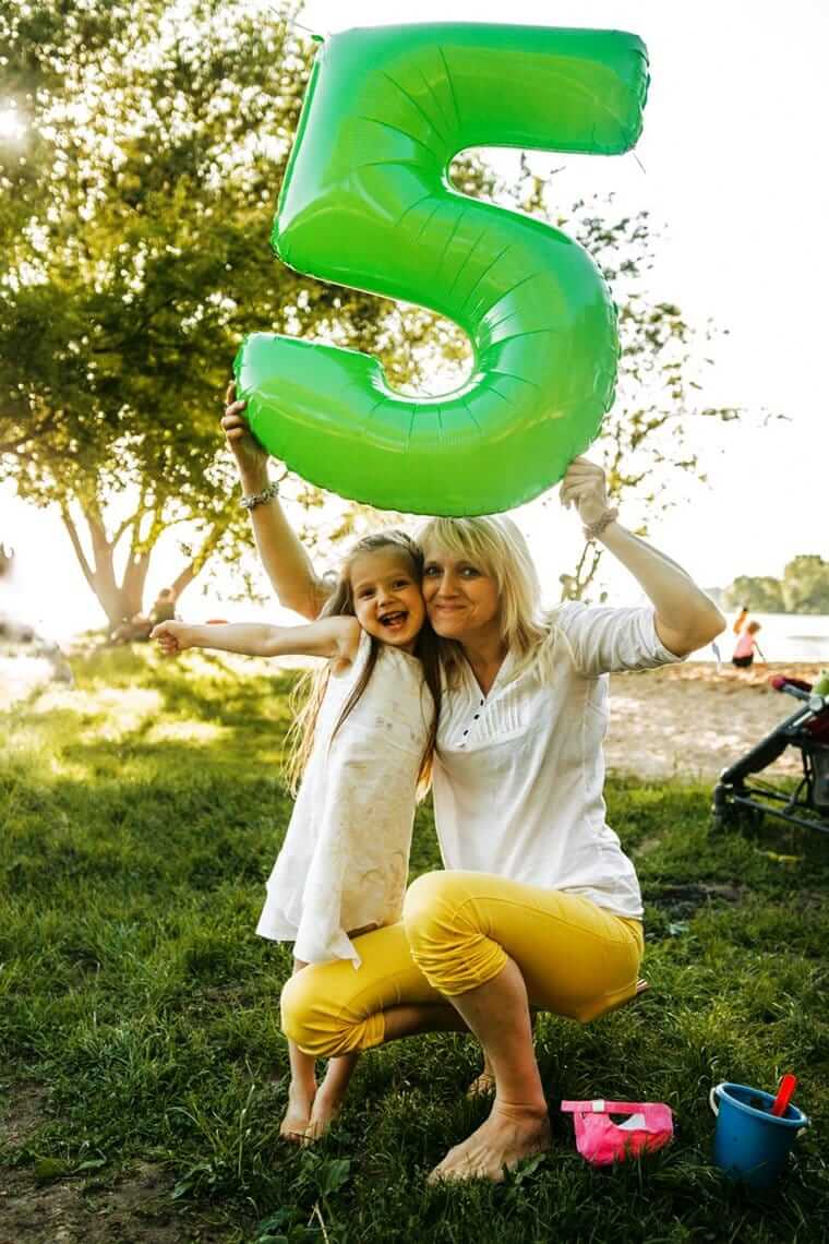 5. Lebensjahr, 5 Jahre (Mutter und Tochter mit Ballon in Form einer 5)