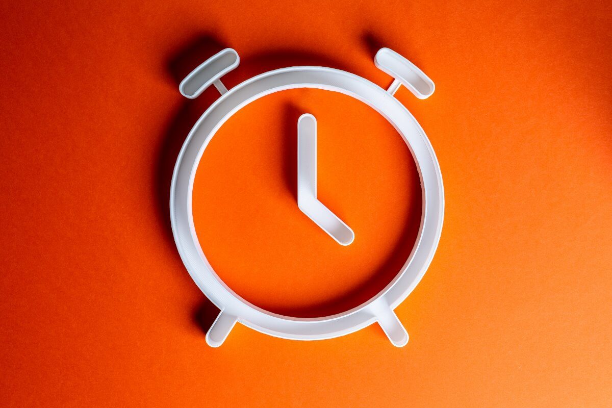 Weiße Uhr vor orangem Hintergrund