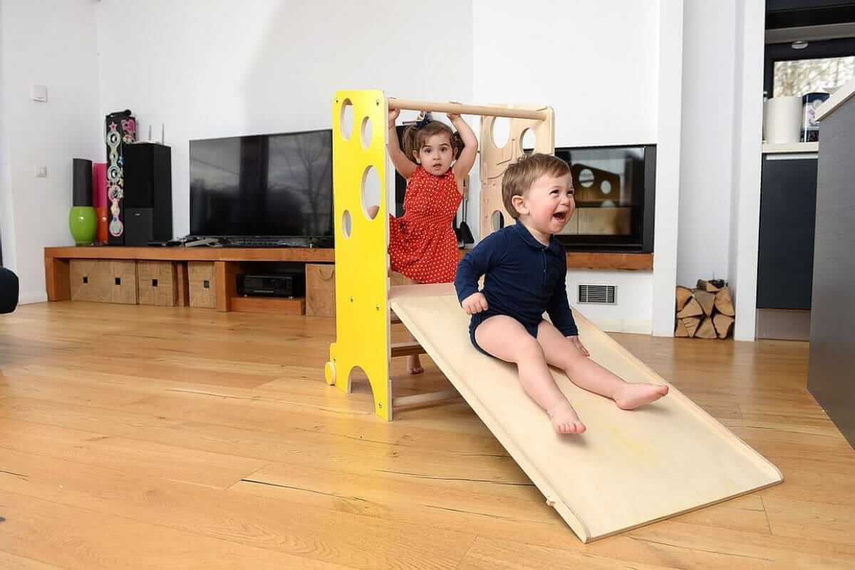 2 Kleinkinder rutschen auf dem Montessori Lernturm