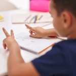 Hausaufgabenhilfe (Adorable hispanic toddler doing mathematics exercise counting with fingers at classroom)