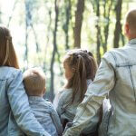 Digital Detox (Mann und Frau halten Händchen mit Jungen und Mädchen und schauen tagsüber auf grüne Bäume)