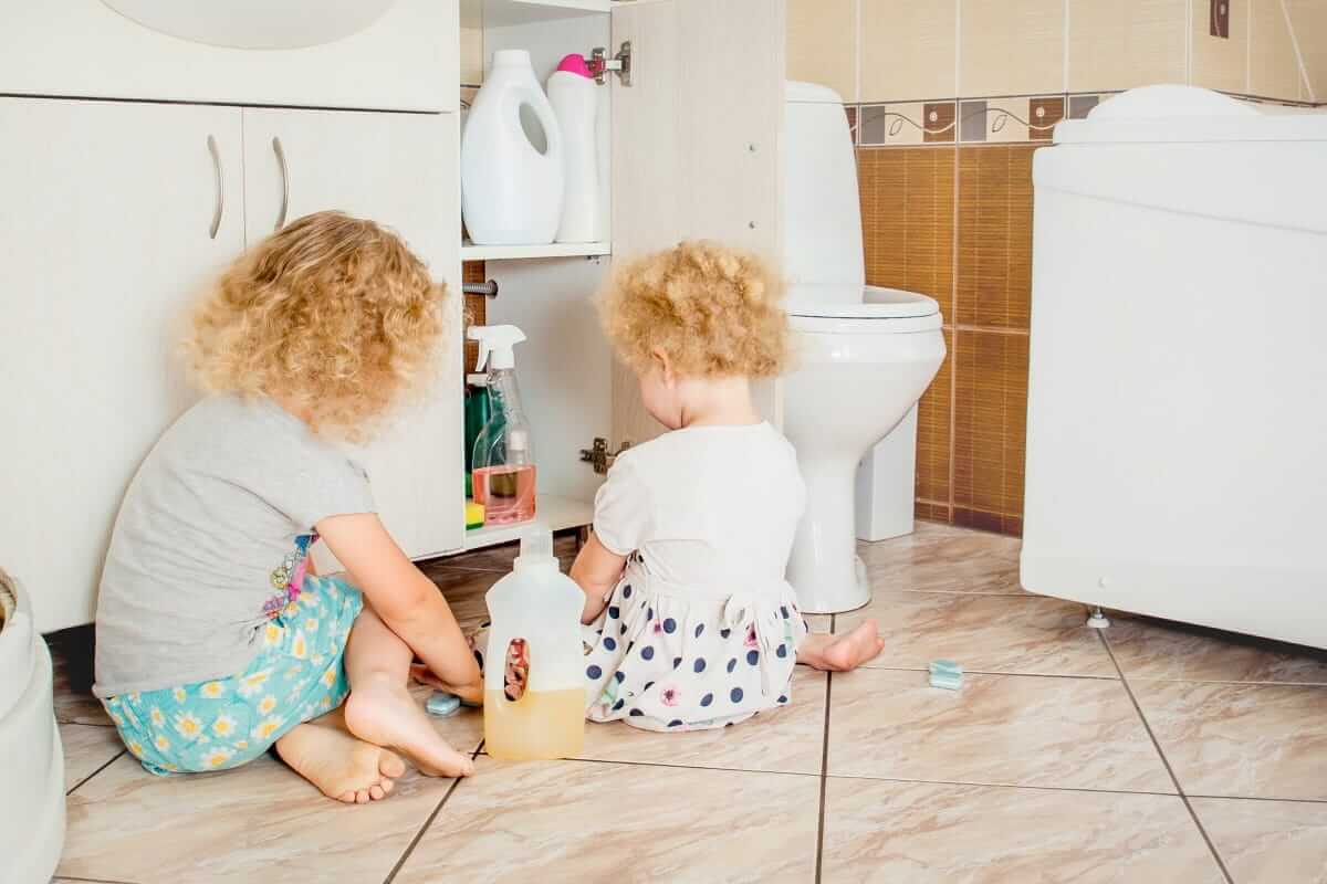 Kindersicherheit, Haushaltssicherheit (Unattended children play quietly at bathroom with dangerous household chemicals. Safety hazard at home concept. Keep away from children`s reach.)