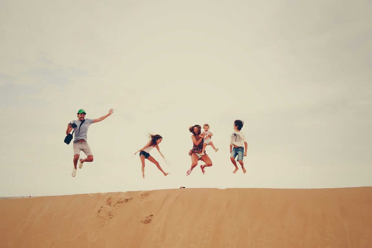 Familienurlaub, Spartipps (Menschen, die auf Sand springen)