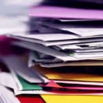 Steuererklärung (Bunter Papierstapel mit Unterlagen – Symbol für Steuererklärung, Familienfinanzen und die Zettelwirtschaft im Alltag mit Kind)