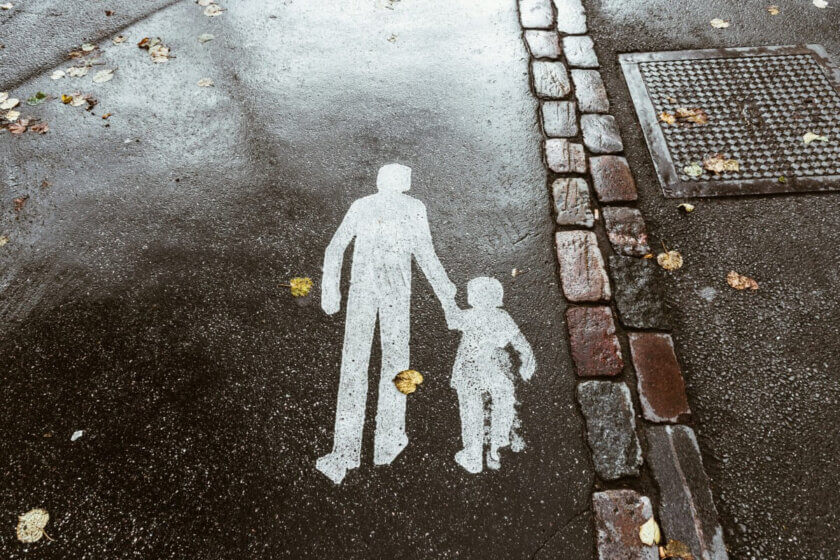 Kindergeld / Symbolische Straßenmarkierung von Erwachsenem und Kind, die Hand in Hand gehen – Sinnbild für Familie, Verantwortung und staatliche Unterstützung.
