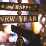 Top 10 / Beiträge 2025 (Dekoratives Holzschild mit der Aufschrift „Happy New Year“, umgeben von warmen Lichtern und Bokeh im Hintergrund.)