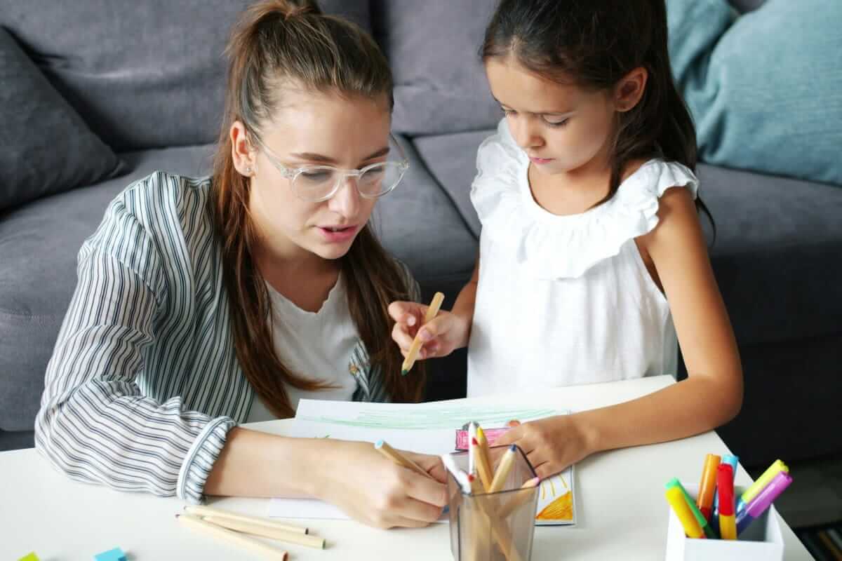 Warum gemeinsame Hobbys Kindern mehr Selbstvertrauen geben Selbstvertrauen, Frau und Mädchen malen gemeinsam am Tisch und arbeiten konzentriert an einem Bild.