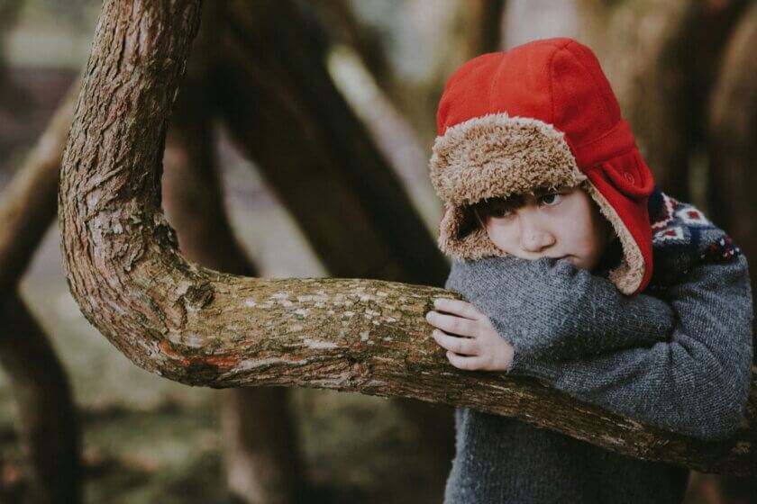 Langeweile / Nachdenkliches Kind lehnt an einem Baum und verbringt ruhige Zeit allein in der Natur