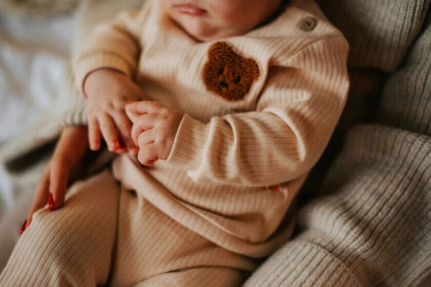 Babyjahre (Baby liegt entspannt im Arm einer Bezugsperson, ruhiger Moment im Alltag)