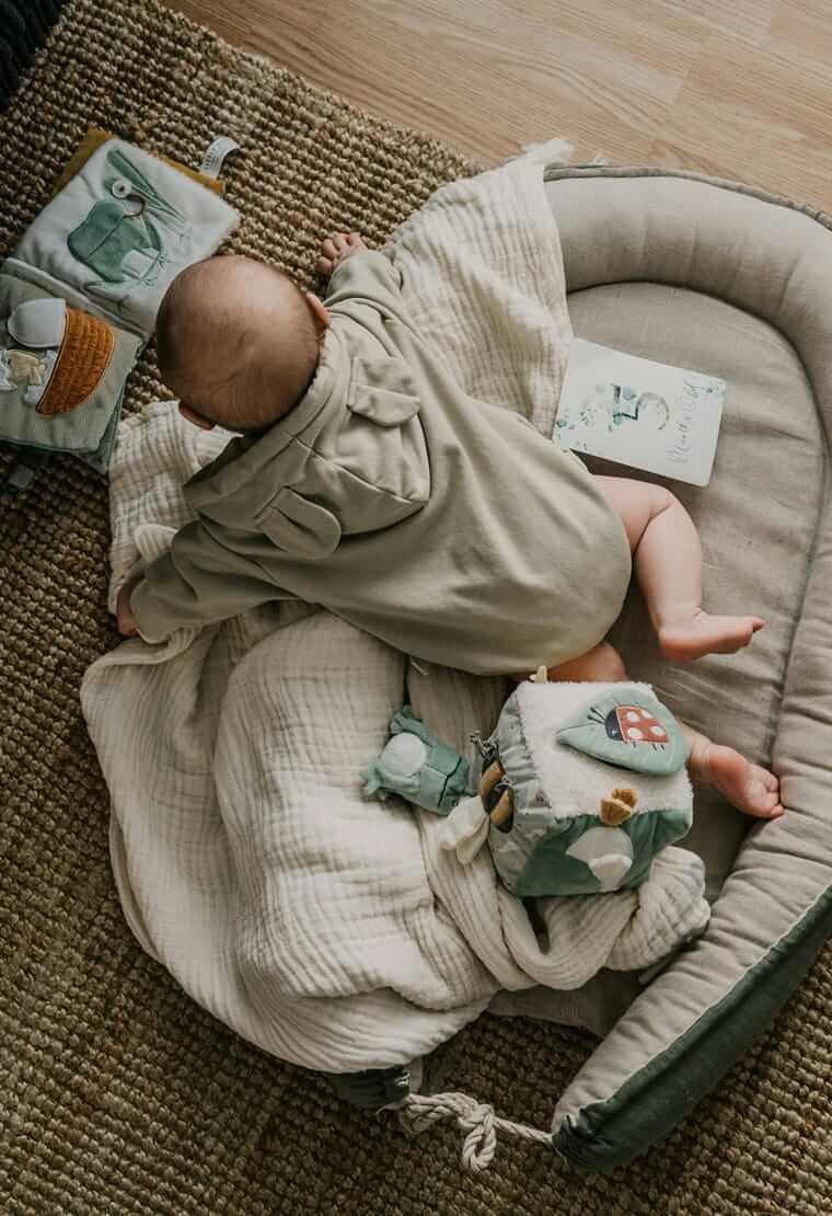 Entwicklung / Baby liegt entspannt auf einer Decke und erkundet seine Umgebung in ruhiger Atmosphäre