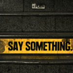 Wenn Kinder weniger erzählen / Schild mit der Aufschrift ‚Say something‘ als Symbol für die Aufforderung, ins Gespräch zu kommen.