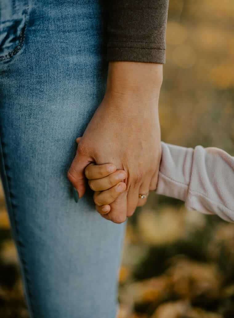 Betreuung / Nahaufnahme zweier Hände – eine Kinderhand hält die Hand einer Erwachsenen fest
