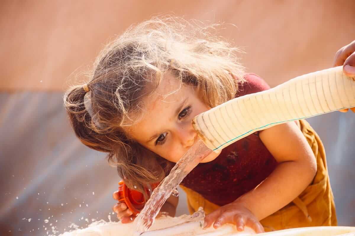 Trink doch mal was – warum das nicht hilft und was stattdessen Trinken, Trink doch mal was / Kind spielt mit Wasser und trinkt daraus im Freien