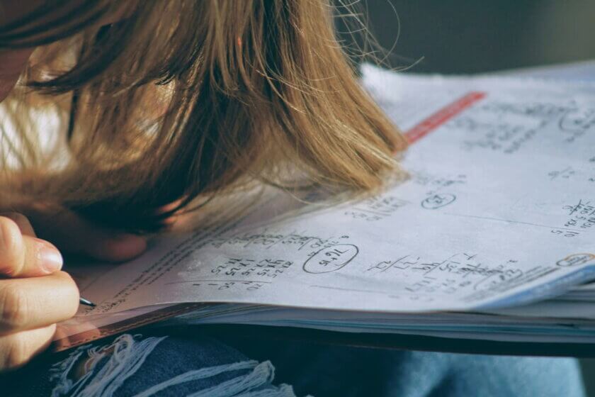 Hausaufgaben / Kind lehnt den Kopf über ein vollgeschriebenes Schulheft
