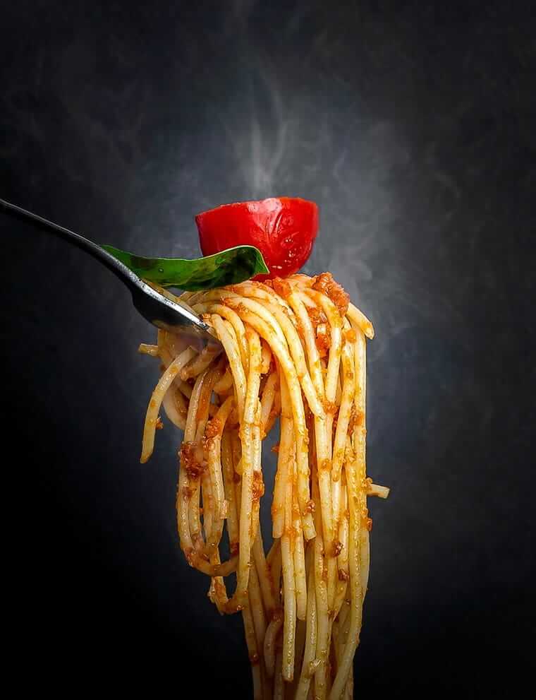 Immer das Gleiche auf dem Teller – warum das völlig okay ist Spaghetti auf einer Gabel mit Tomate und Basilikum vor dunklem Hintergrund – inszeniertes Essen vs. Kinderalltag