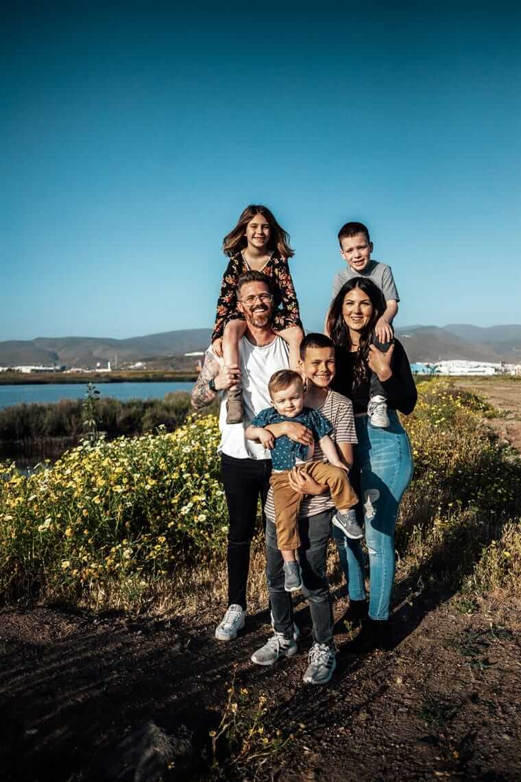 Familie mit vier Kindern unterschiedlichen Alters steht zusammen am Wasser – verschiedene Bedürfnisse beim Familienurlaub