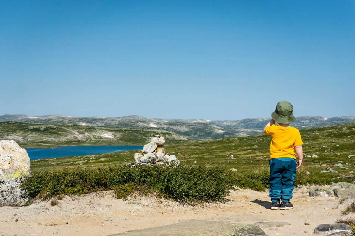Bergurlaub / Kind betrachtet einen Bergsee in den Bergen – solche Momente bleiben beim Wandern mit Kindern im Gedächtnis