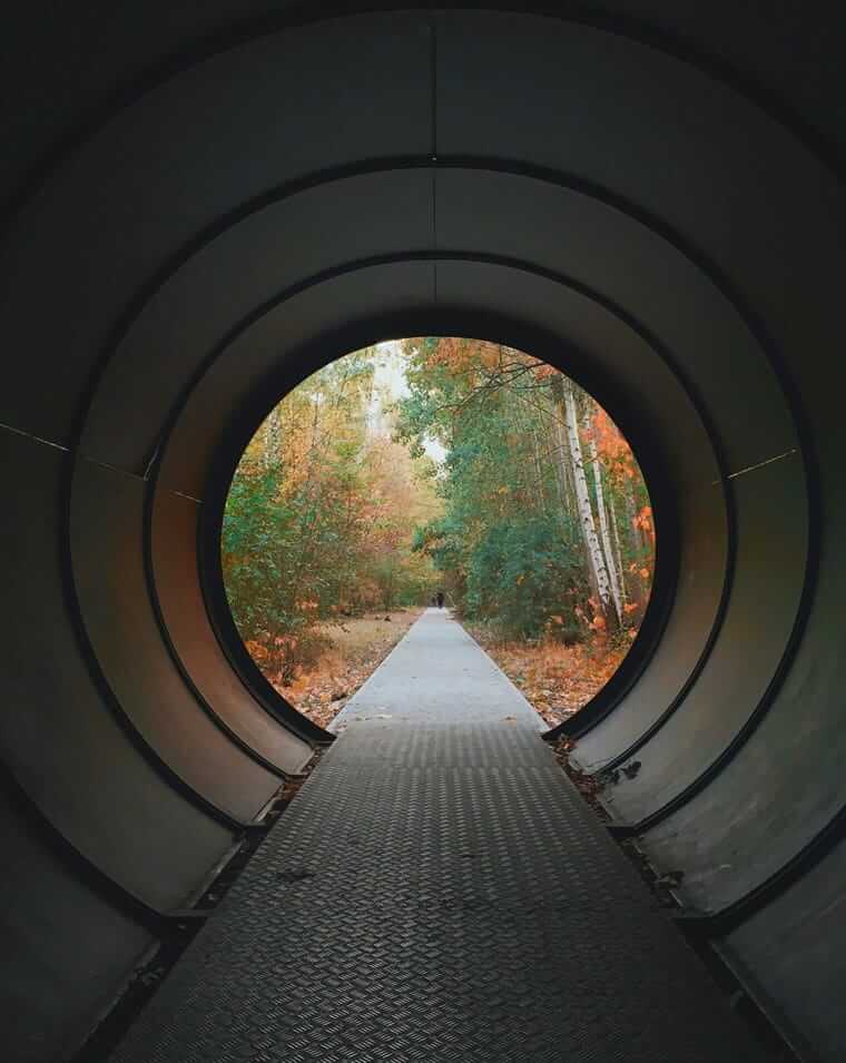Sorgen, Eltern, Kinder / Blick durch eine runde Tunnelöffnung in einen herbstlichen Wald – Symbol für eingeschränkte Wahrnehmung und den Blick, der sich weiten kann.