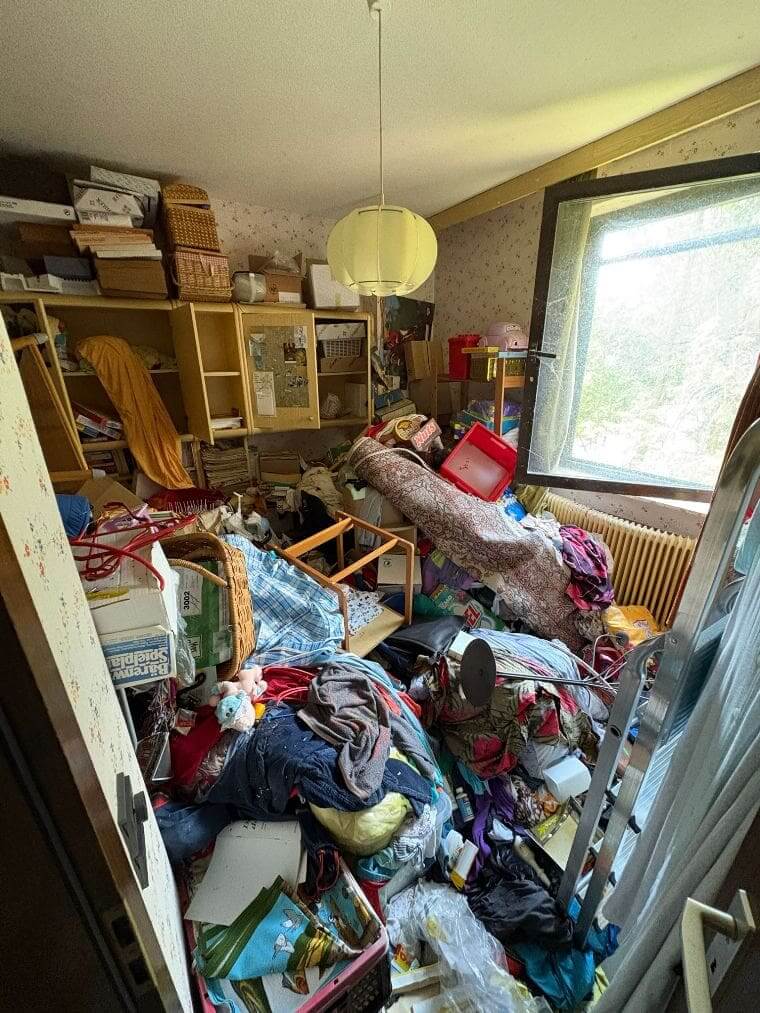 Wenn die Wohnung der Eltern kippt: So hilfst du, ohne Vertrauen zu zerstören Ein vollgestelltes Zimmer mit Möbeln, Kartons und Gegenständen, die kaum noch Platz lassen – Blick in eine Wohnung mit Messie-Syndrom.
