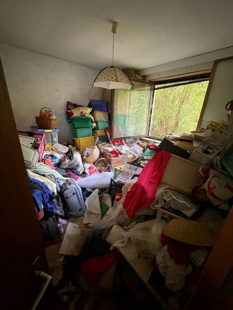 Wenn die Wohnung der Eltern kippt: So hilfst du, ohne Vertrauen zu zerstören Vollgestelltes Zimmer mit Kleidung, Taschen und Kisten auf dem Boden – ein überfüllter Raum in einer Messie-Wohnung.
