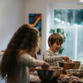 Zwei Kinder stehen gemeinsam in der Küche und rühren in Schüsseln – Kochen als normaler Teil des Familienalltags