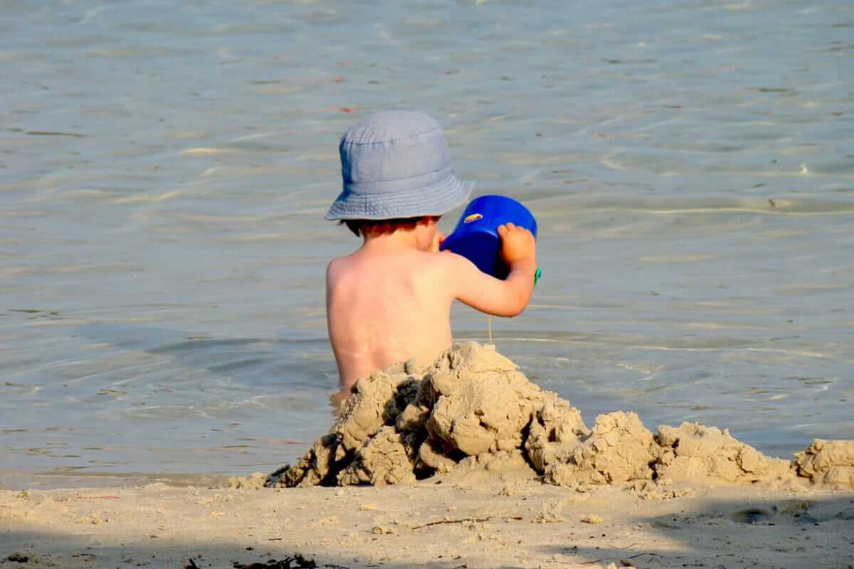 Kleinkind baut eine Sandburg am Wasser – klassischer Strandtag bei einem Ostsee-Urlaub mit Kindern