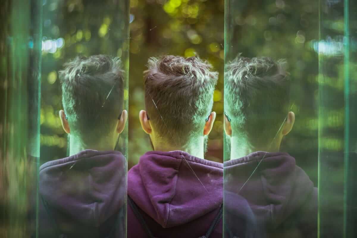 Jugendlicher von hinten, mehrfach in Glasscheiben gespiegelt – Symbol für Identitätsfindung in der Pubertät