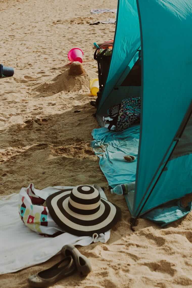 Strandlager einer Familie mit Windschutz, Sonnenhut und Spielzeug – gut ausgerüstet für den Ostsee-Urlaub mit Kindern