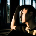 Pubertät bei Jungs / Jugendlicher im Gegenlicht, Lichtstreifen fallen über Gesicht und Hand, nachdenklicher Blick zur Seite