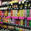 Vollständig gefüllte Supermarktregalwand mit bunten Getränkedosen in allen Farben – Symbol für die Reizüberflutung durch Produktwerbung im Alltag.
