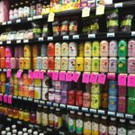 Vollständig gefüllte Supermarktregalwand mit bunten Getränkedosen in allen Farben – Symbol für die Reizüberflutung durch Produktwerbung im Alltag.
