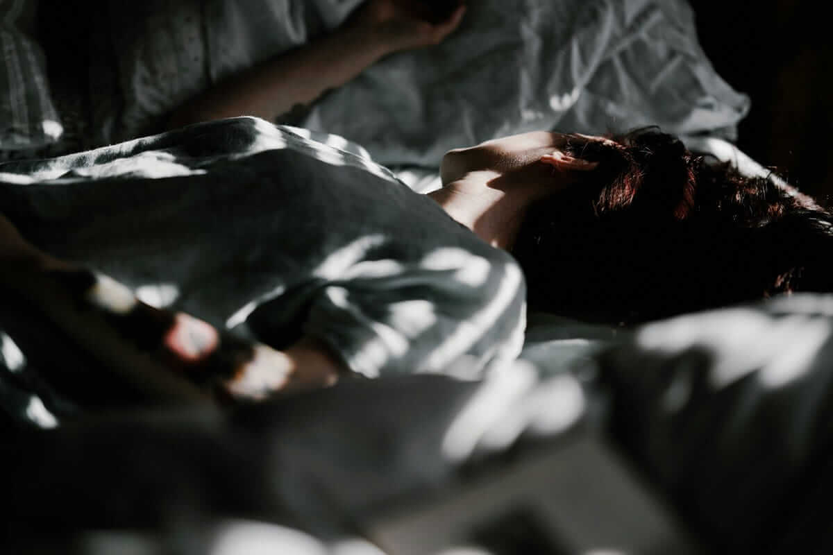 Schlafprobleme bei Schulkindern / Person liegt wach im Bett, Lichtmuster auf der Bettwäsche