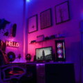 Gaming-Ecke im Neonlicht: Schreibtisch mit Monitor, PC-Gehäuse und Bürostuhl vor einer Wand mit Weltkarte