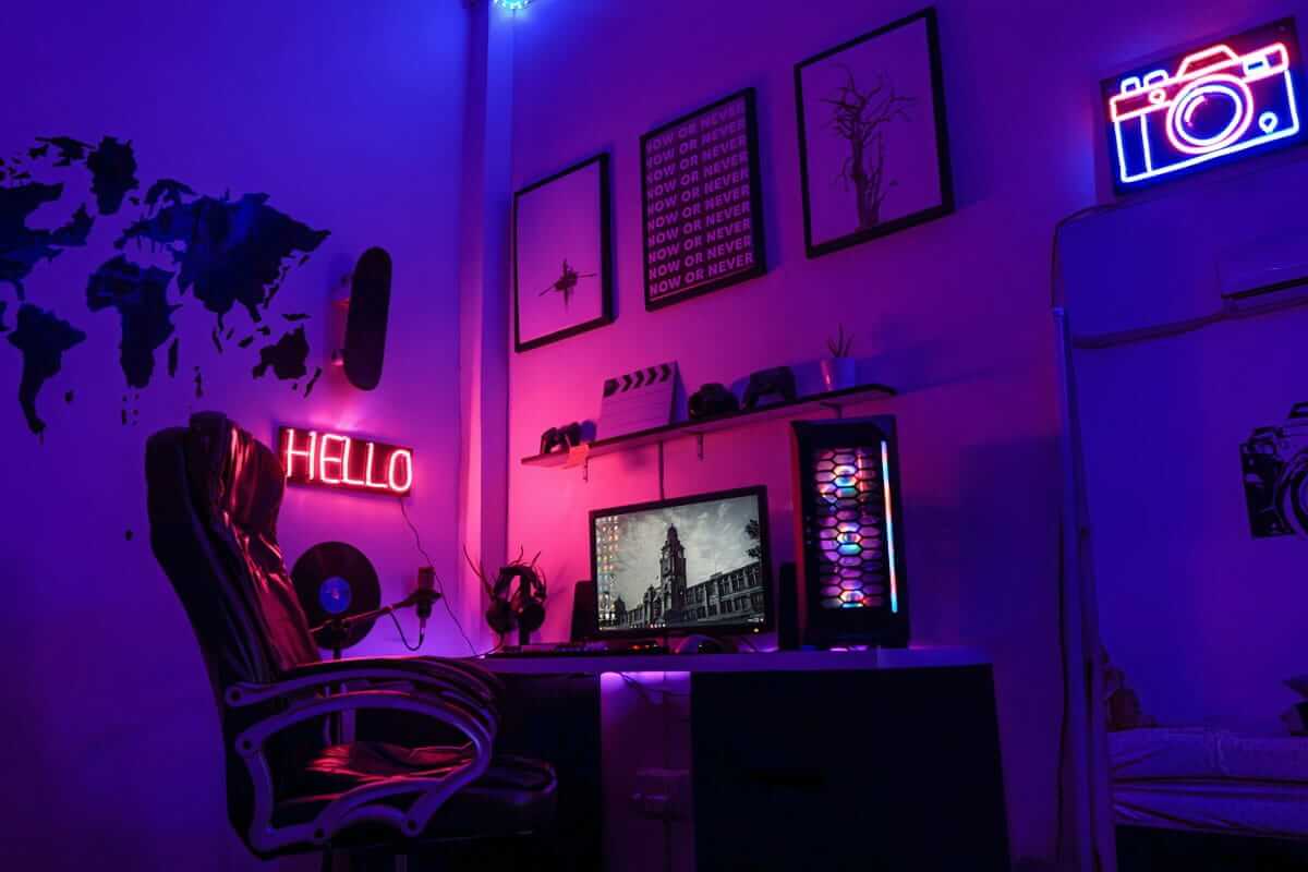 Der erste Gaming-PC fürs Kind: Was Eltern über Budget, Spiele, USK und Jugendschutz wissen sollten Gaming-Ecke im Neonlicht: Schreibtisch mit Monitor, PC-Gehäuse und Bürostuhl vor einer Wand mit Weltkarte